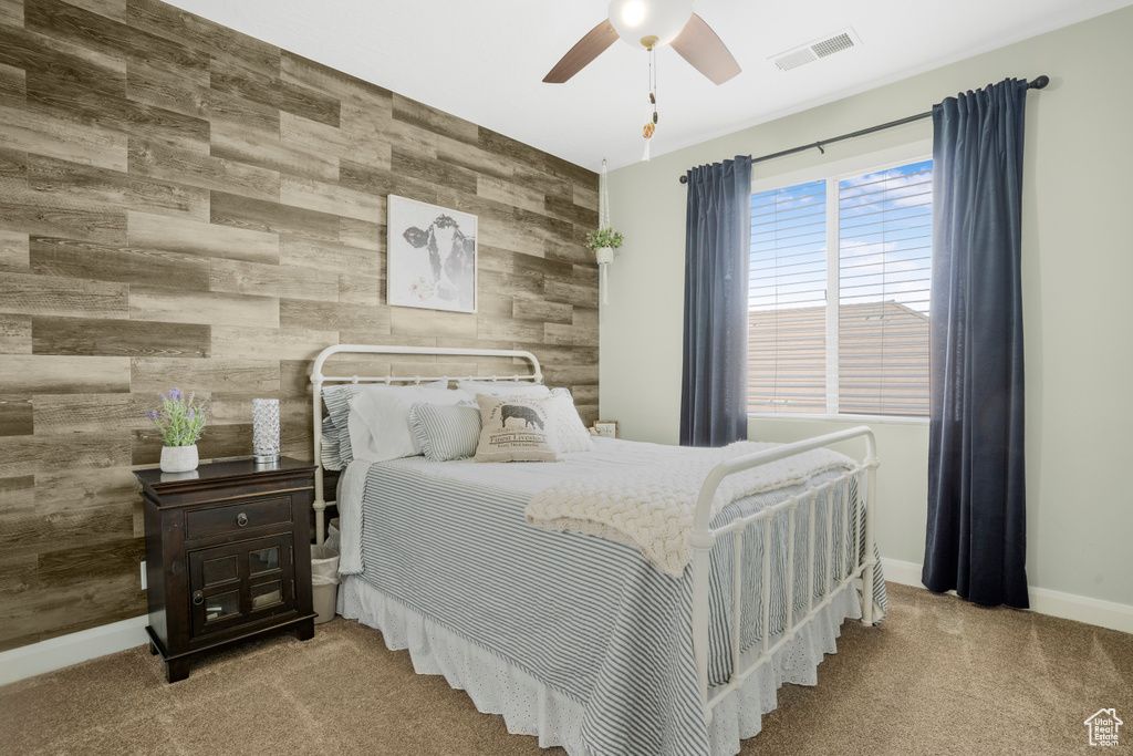 Bedroom featuring wood walls, an accent wall, carpet floors, baseboards, and ceiling fan