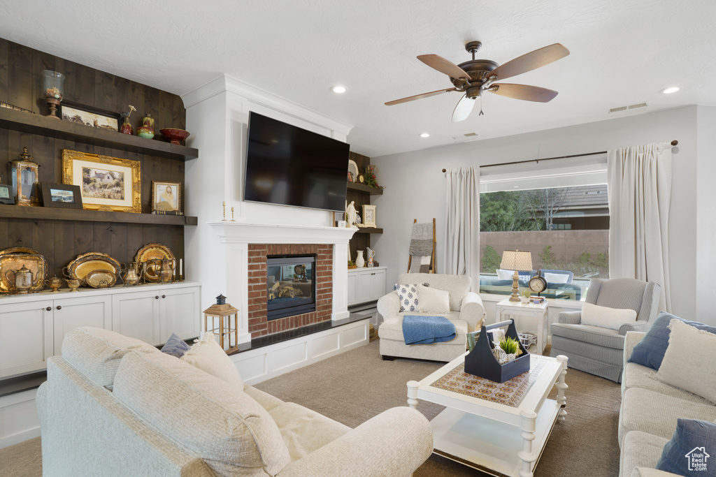 Carpeted living area with ceiling fan, recessed lighting, and a fireplace