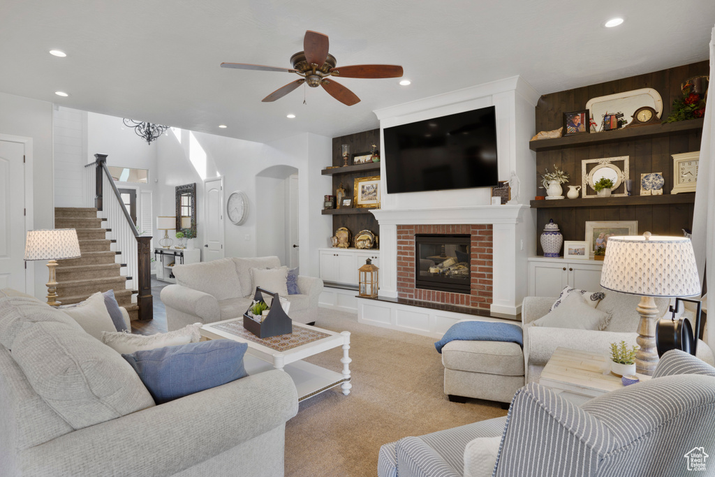 Carpeted living area with a ceiling fan, arched walkways, recessed lighting, stairs, and built in features