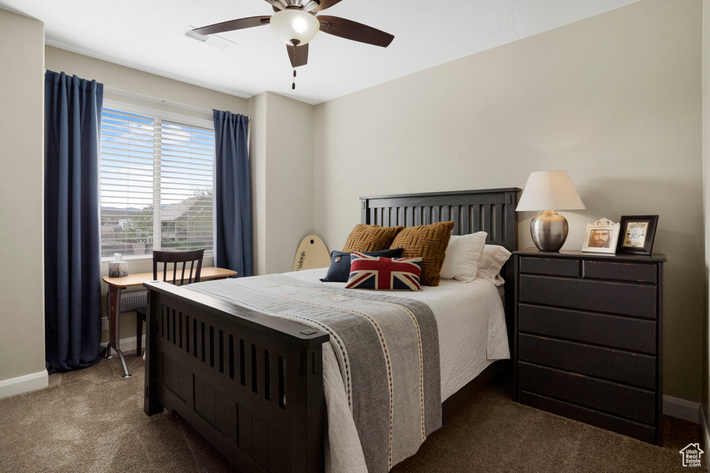 Bedroom with dark colored carpet, baseboards, and ceiling fan
