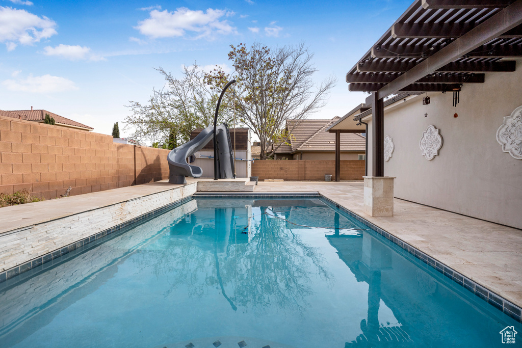 View of swimming pool featuring a water slide, a fenced backyard, a pergola, and a patio area
