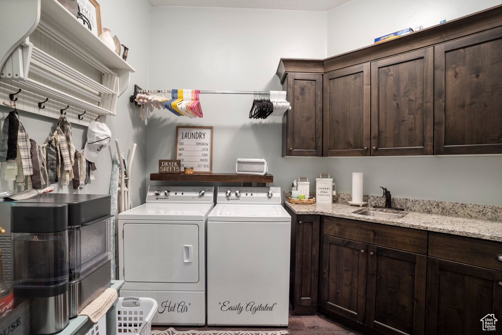 Laundry room featuring washing machine and clothes dryer, cabinet space, and wood finished floors