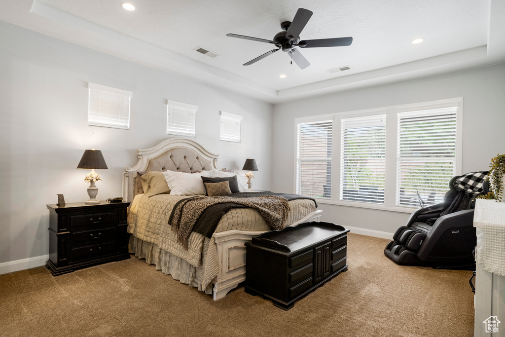 Bedroom featuring light carpet, baseboards, recessed lighting, a raised ceiling, and a ceiling fan