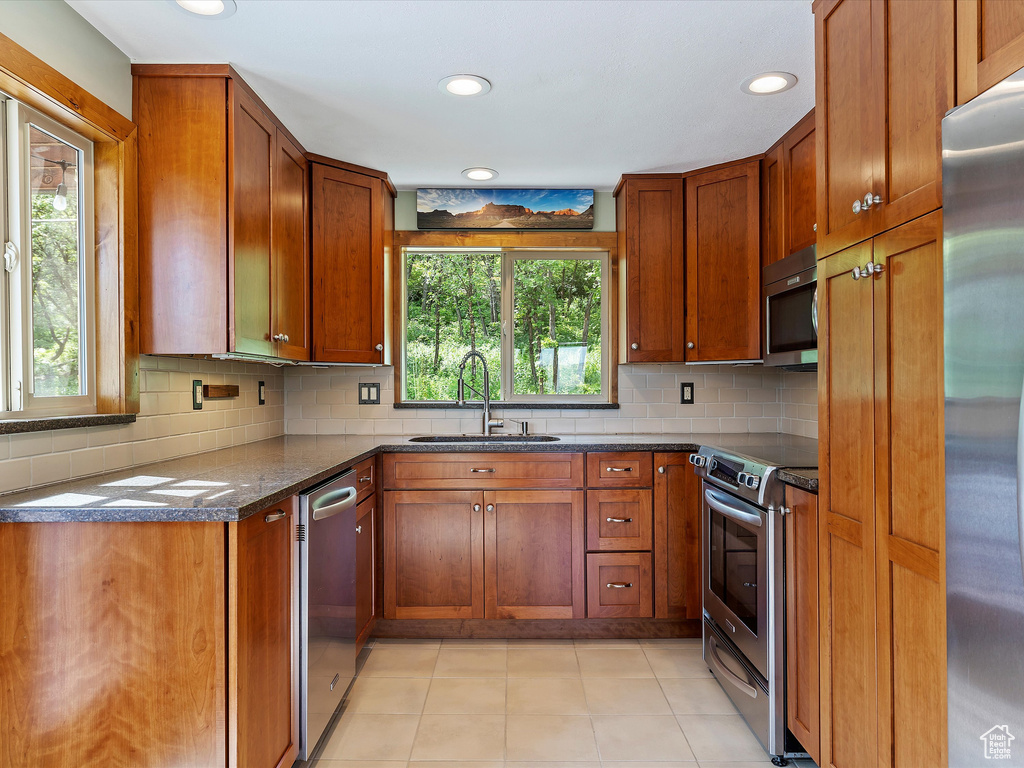 Kitchen featuring stainless steel appliances, a sink, brown cabinets, tasteful backsplash, and recessed lighting