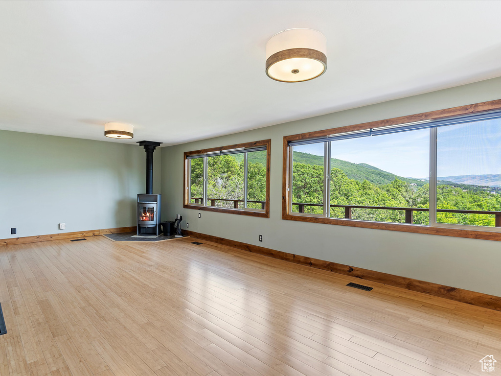 Unfurnished living room with baseboards, a wood stove, and wood finished floors
