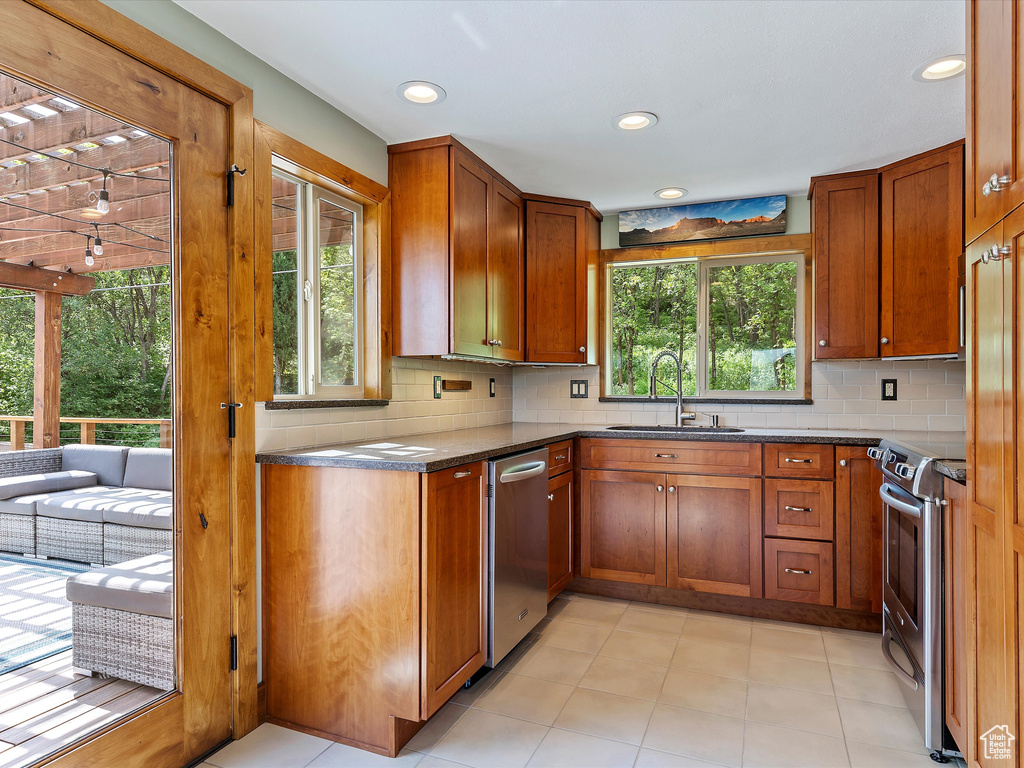 Kitchen with a sink, stainless steel appliances, brown cabinets, backsplash, and recessed lighting