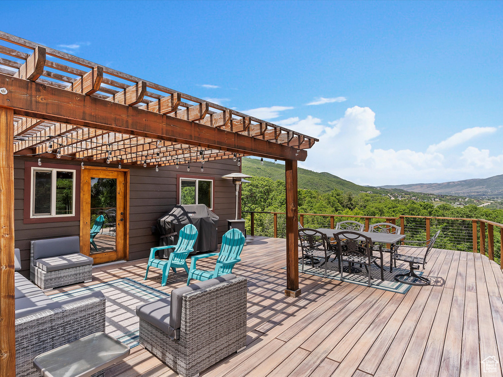 Wooden terrace featuring outdoor dining area, a pergola, a mountain view, and area for grilling