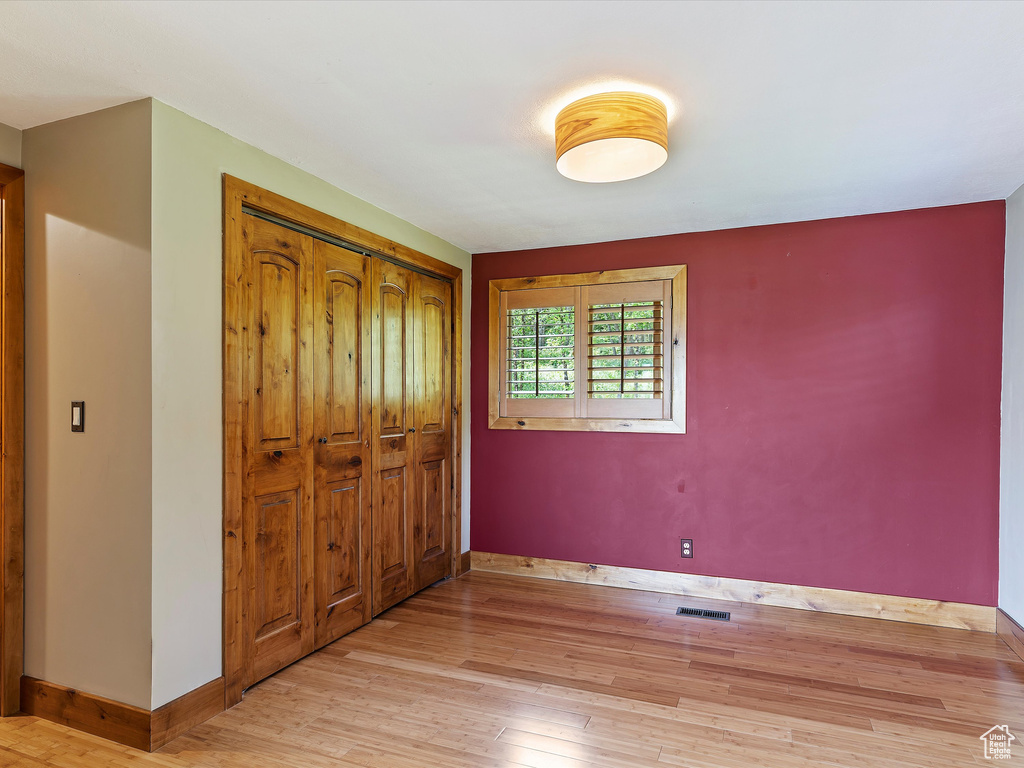 Unfurnished bedroom with wood finished floors, baseboards, and a closet