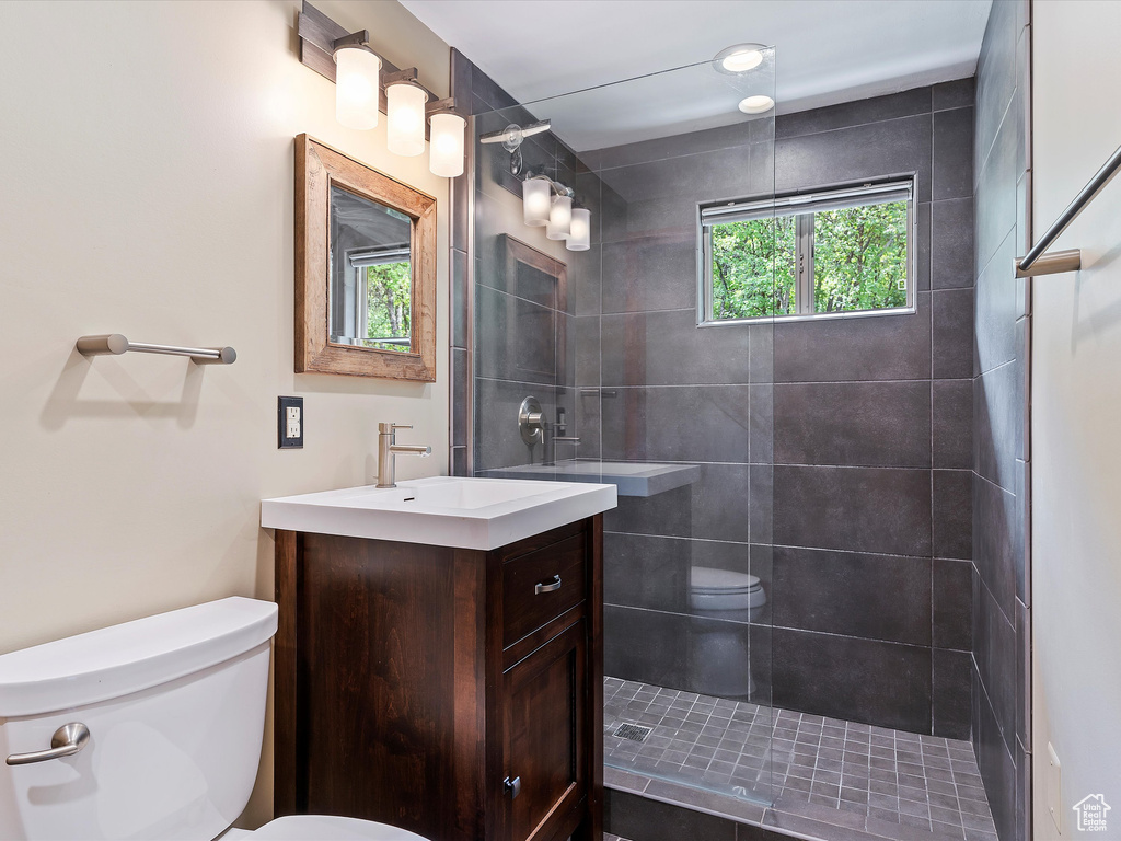 Bathroom with toilet, vanity, and tiled shower
