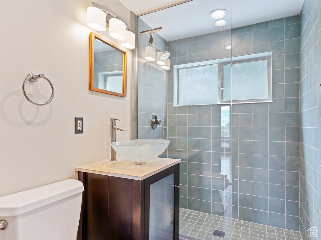 Bathroom featuring toilet, a tile shower, and vanity