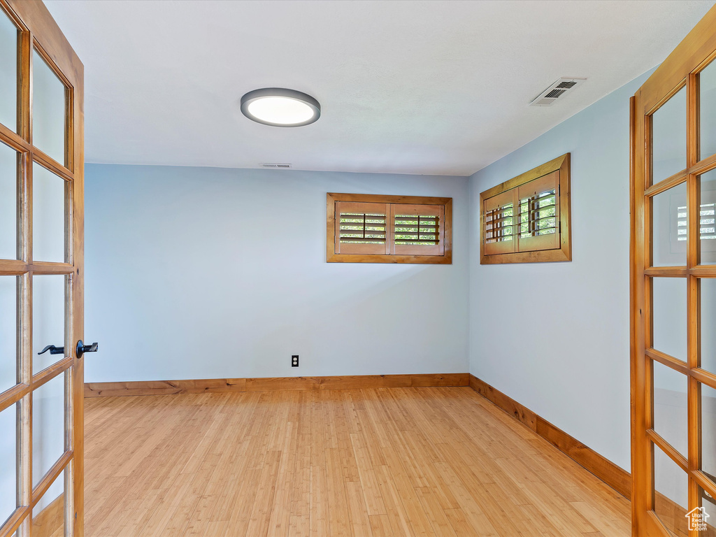 Spare room with wood finished floors, french doors, and baseboards