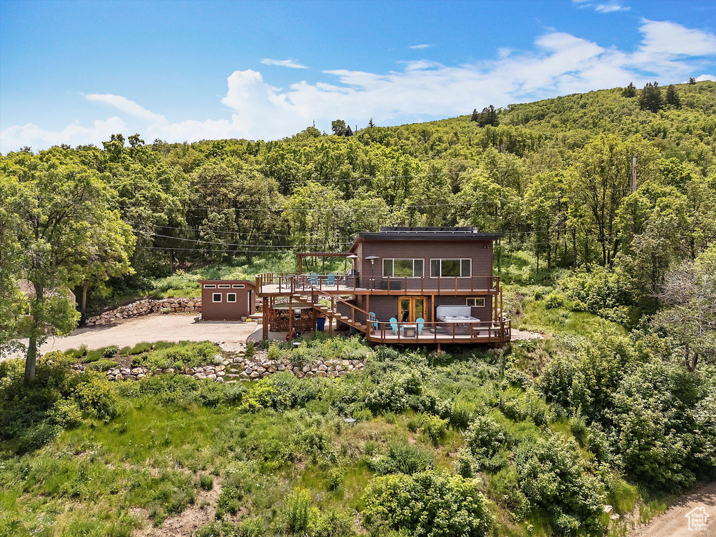 Rear view of house with a wooded view and a deck