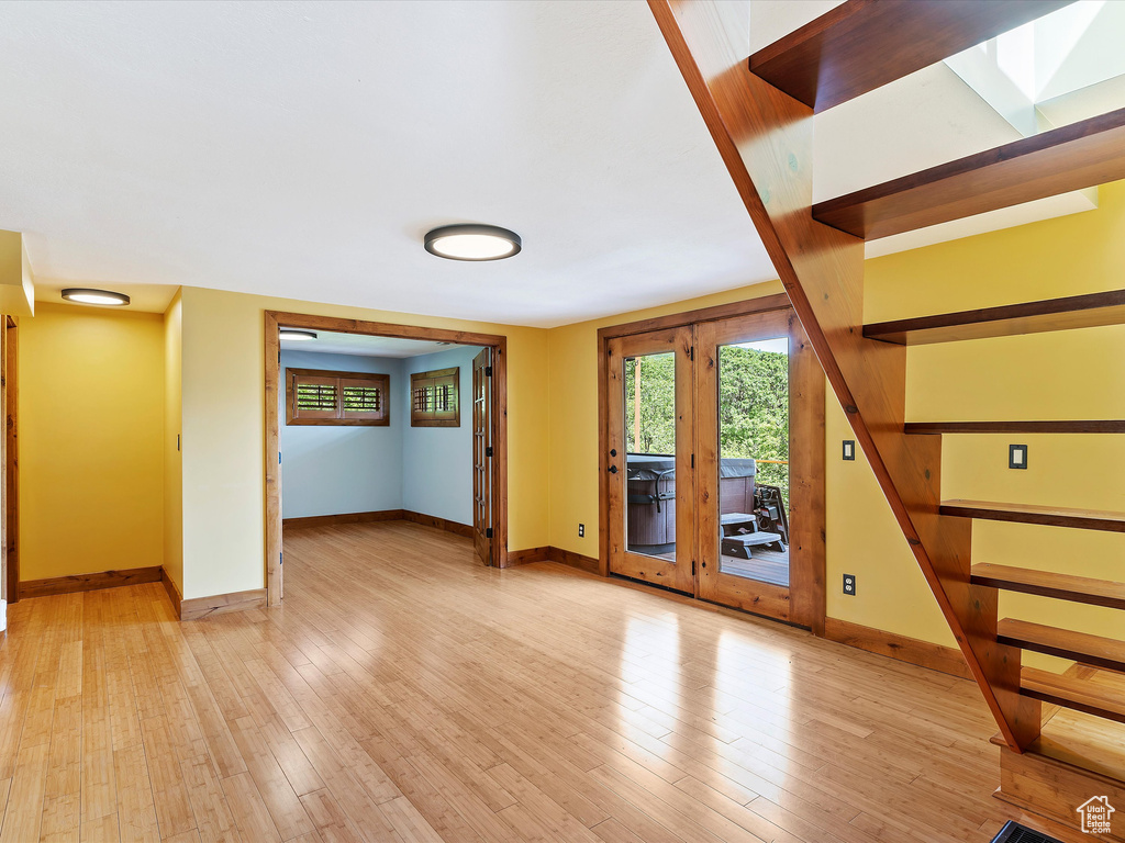 Unfurnished living room with baseboards, stairs, and light wood-style flooring