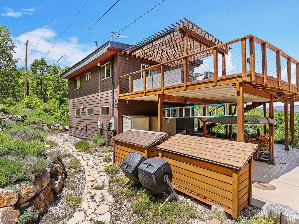 Back of property featuring a deck and a pergola