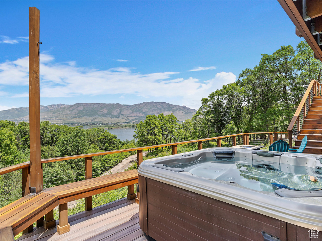 Deck with a hot tub, stairs, and a water and mountain view