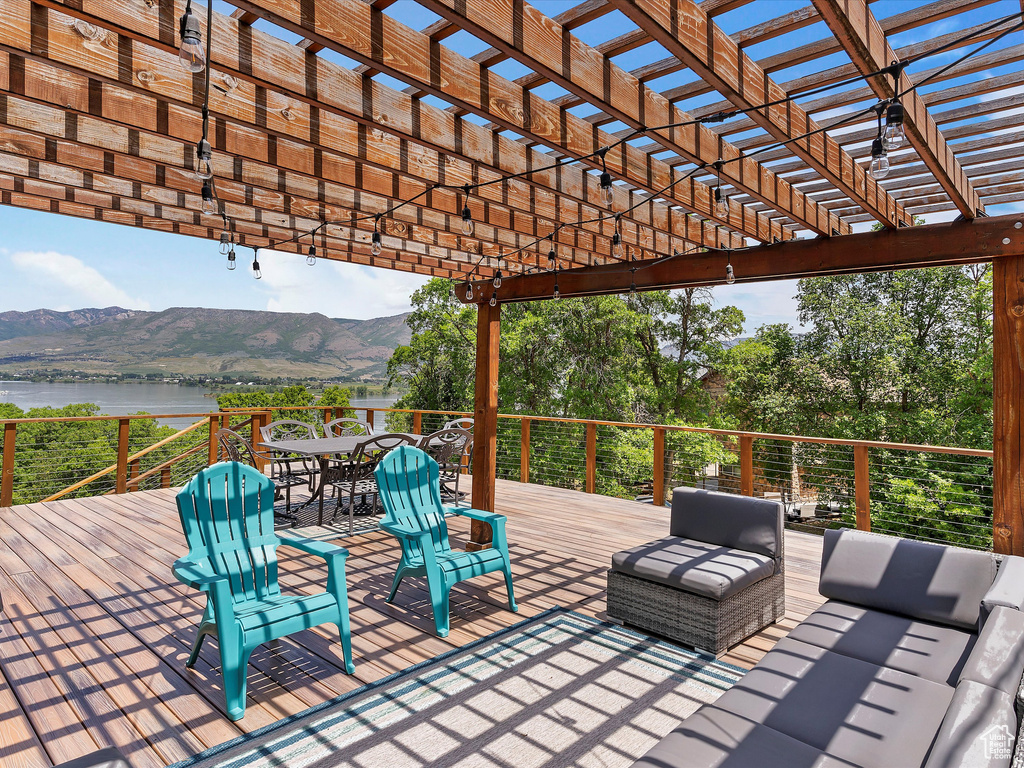 Deck with a pergola, a water and mountain view, outdoor dining space, and an outdoor living space
