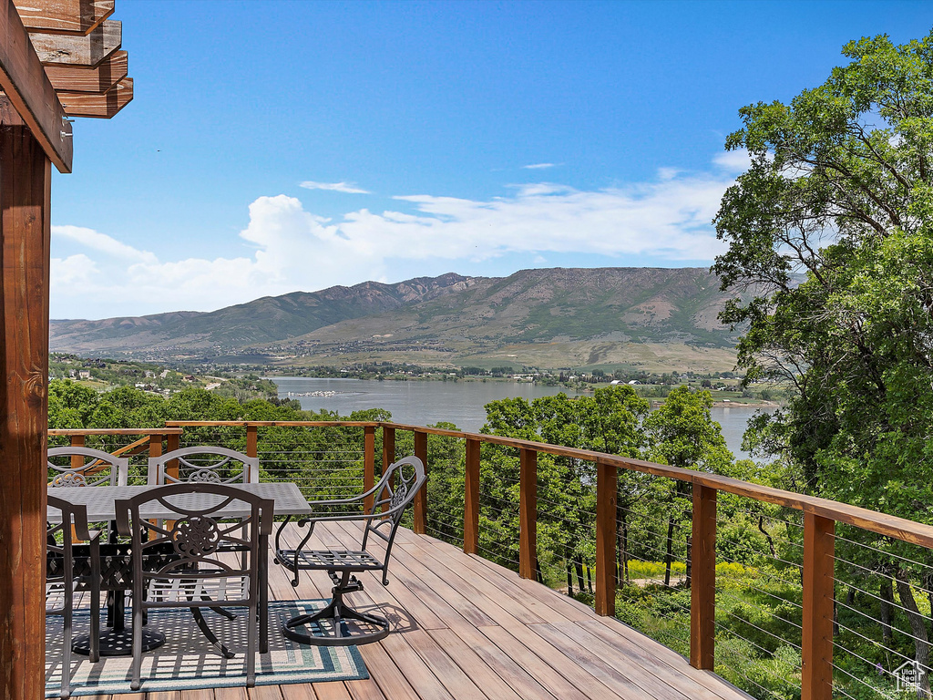 Deck with a water and mountain view and outdoor dining area