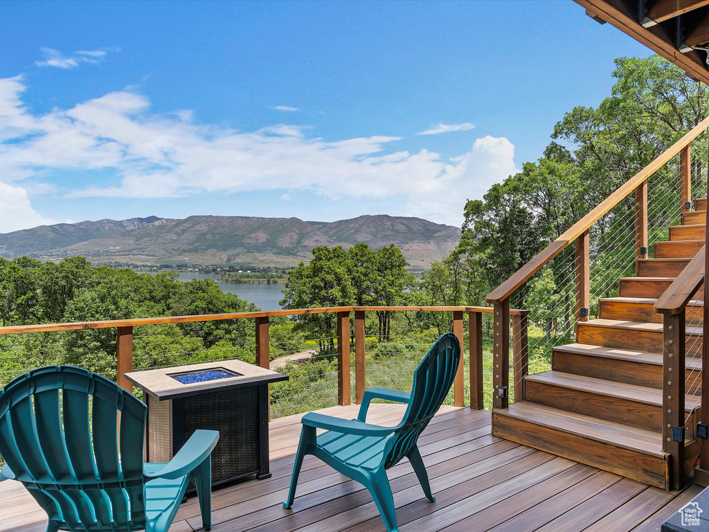 Wooden deck with stairs, a fire pit, and a water and mountain view