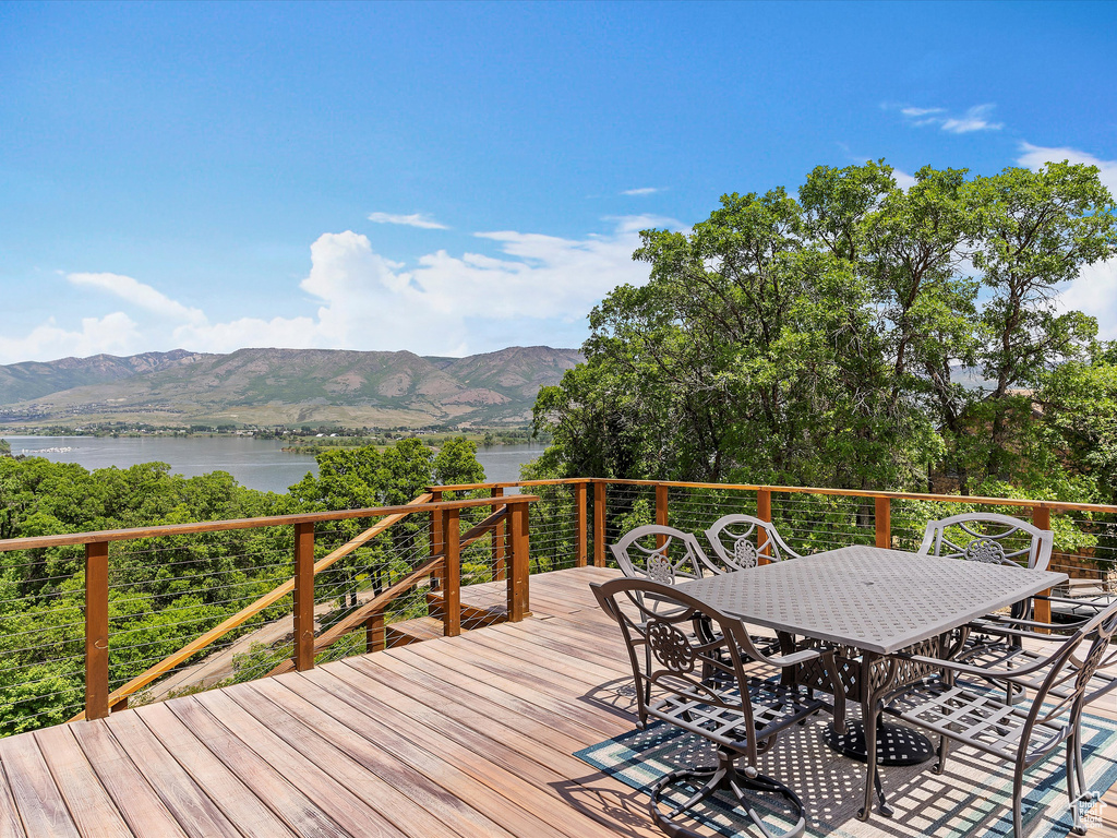 Deck with a water and mountain view and outdoor dining area