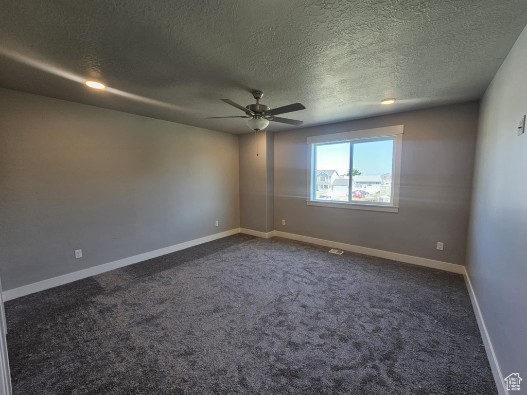 Carpeted empty room with a ceiling fan, a textured ceiling, and baseboards