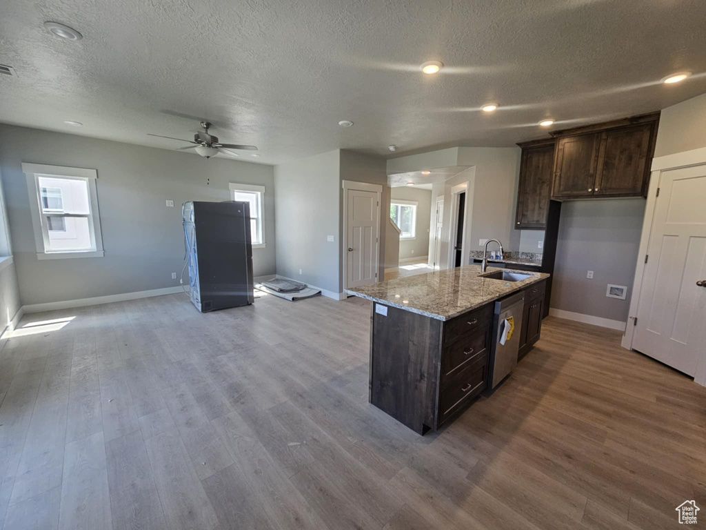 Kitchen featuring a sink, a textured ceiling, open floor plan, wood finished floors, and baseboards