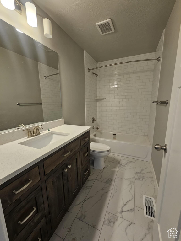 Full bathroom with marble finish flooring, vanity, shower / bath combination, toilet, and a textured ceiling