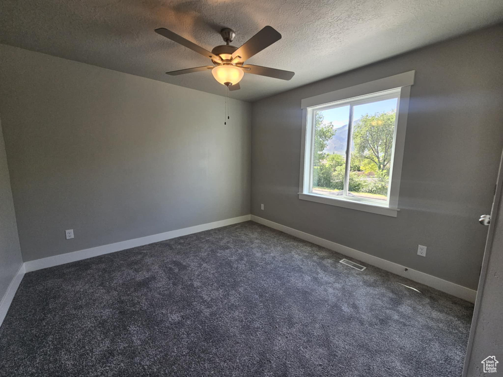 Carpeted spare room with a textured ceiling, ceiling fan, and baseboards