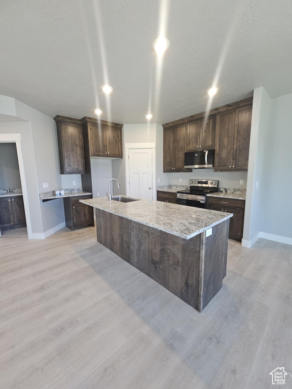 Kitchen with appliances with stainless steel finishes, a sink, baseboards, and dark brown cabinets
