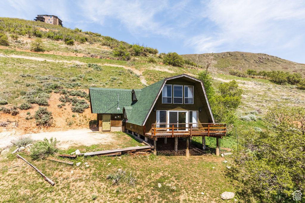 Back of property featuring a deck with mountain view and a gambrel roof