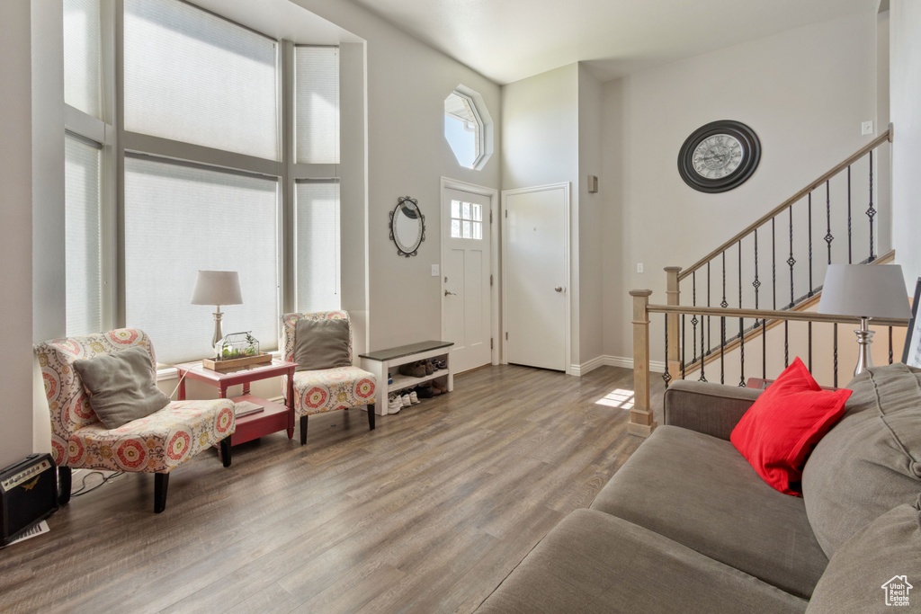Living area with wood finished floors, a towering ceiling, stairs, and baseboards