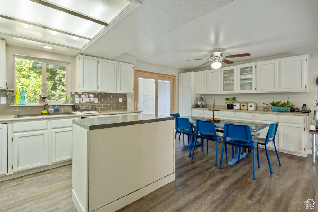 Kitchen featuring a sink, backsplash, wood finished floors, and a ceiling fan
