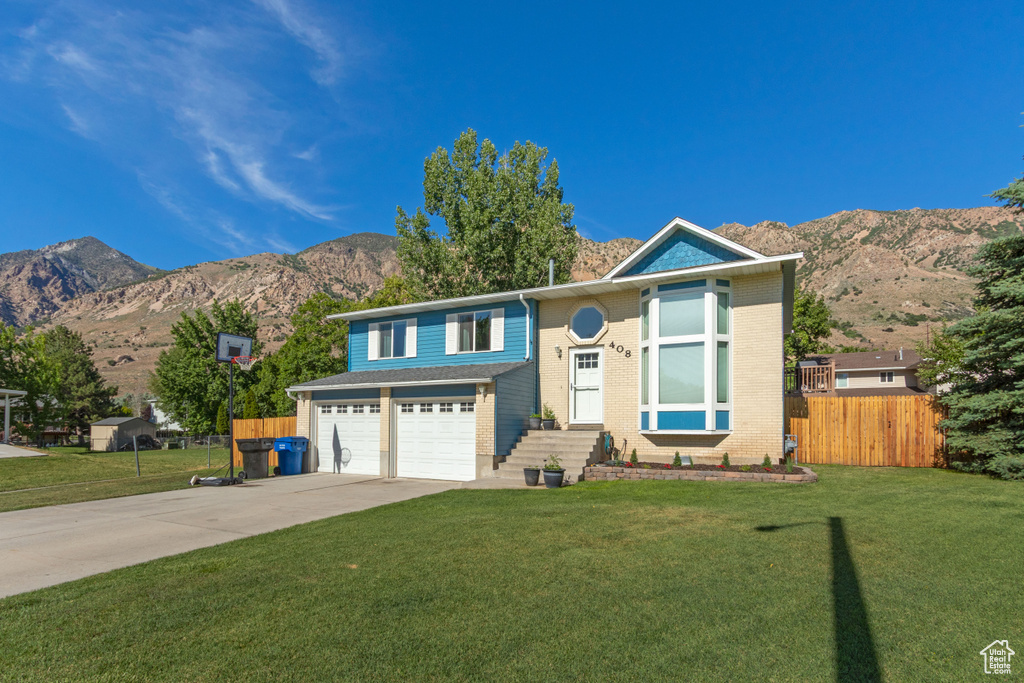 View of front of house with concrete driveway, a mountain view, an attached garage, and brick siding