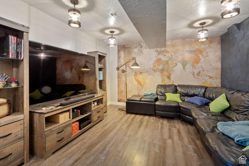 Living area featuring a textured ceiling, wood finished floors, and baseboards