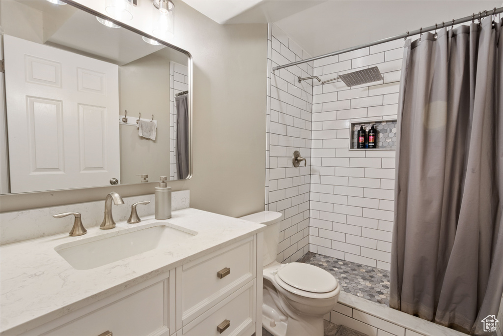 Bathroom with toilet, vanity, and tiled shower