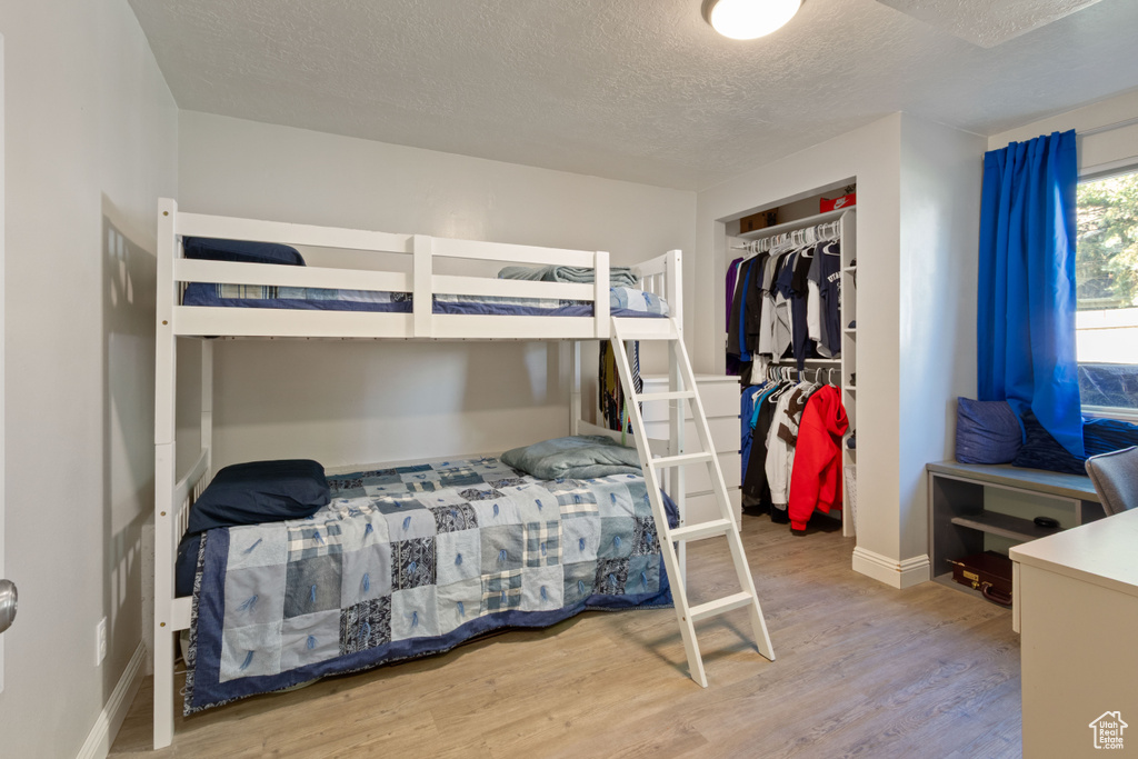Bedroom with a textured ceiling, wood finished floors, a closet, and baseboards