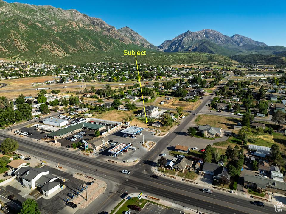 Aerial view of property and surrounding area with a mountainous background and nearby suburban area