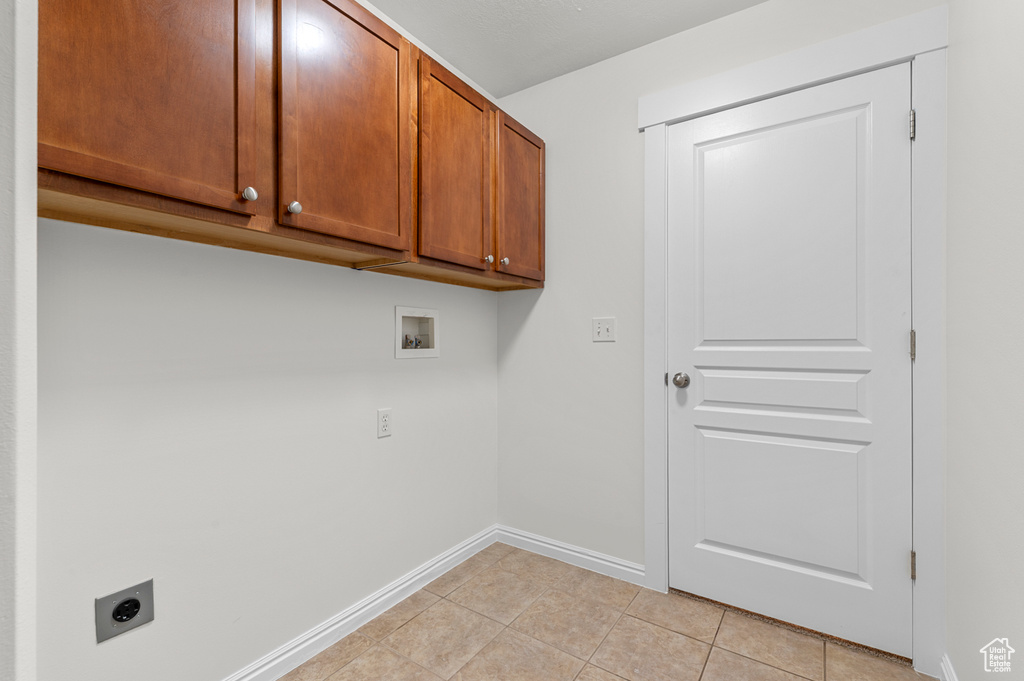 Laundry room with electric dryer hookup, cabinet space, hookup for a washing machine, light tile patterned floors, and baseboards