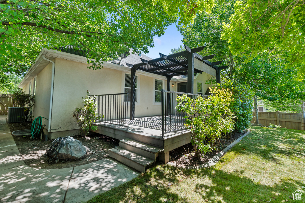 Rear view of property featuring a pergola, stucco siding, a deck, and central AC