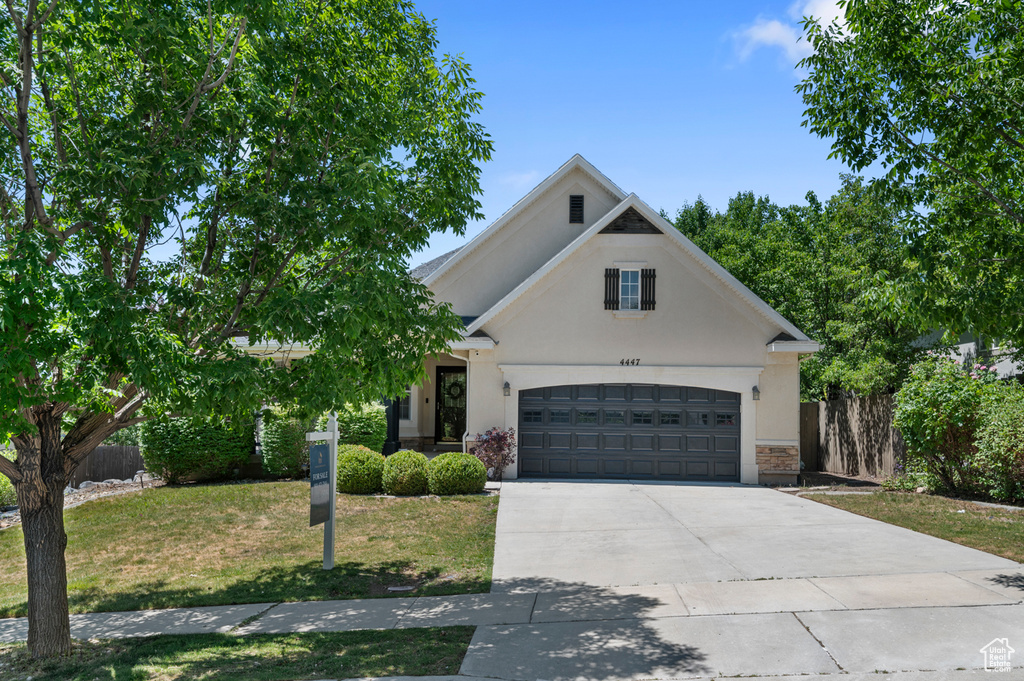 View of front of home with stucco siding, driveway, a garage, and stone siding