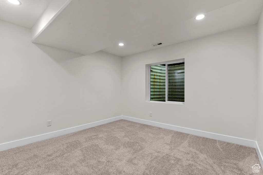 Spare room featuring recessed lighting, light colored carpet, and baseboards