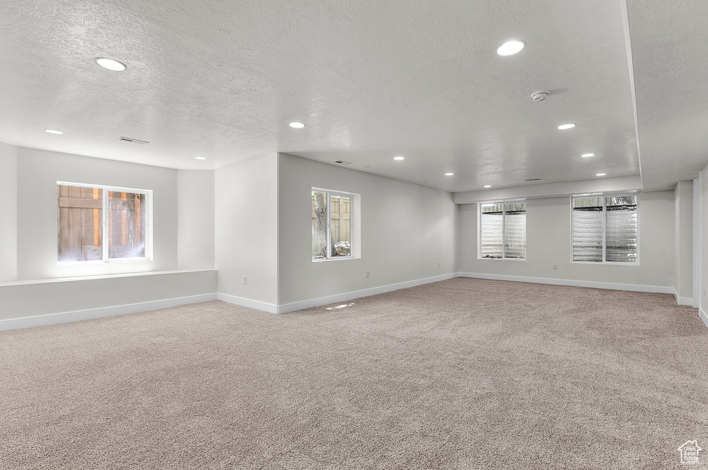 Spare room with recessed lighting, a textured ceiling, carpet floors, and baseboards