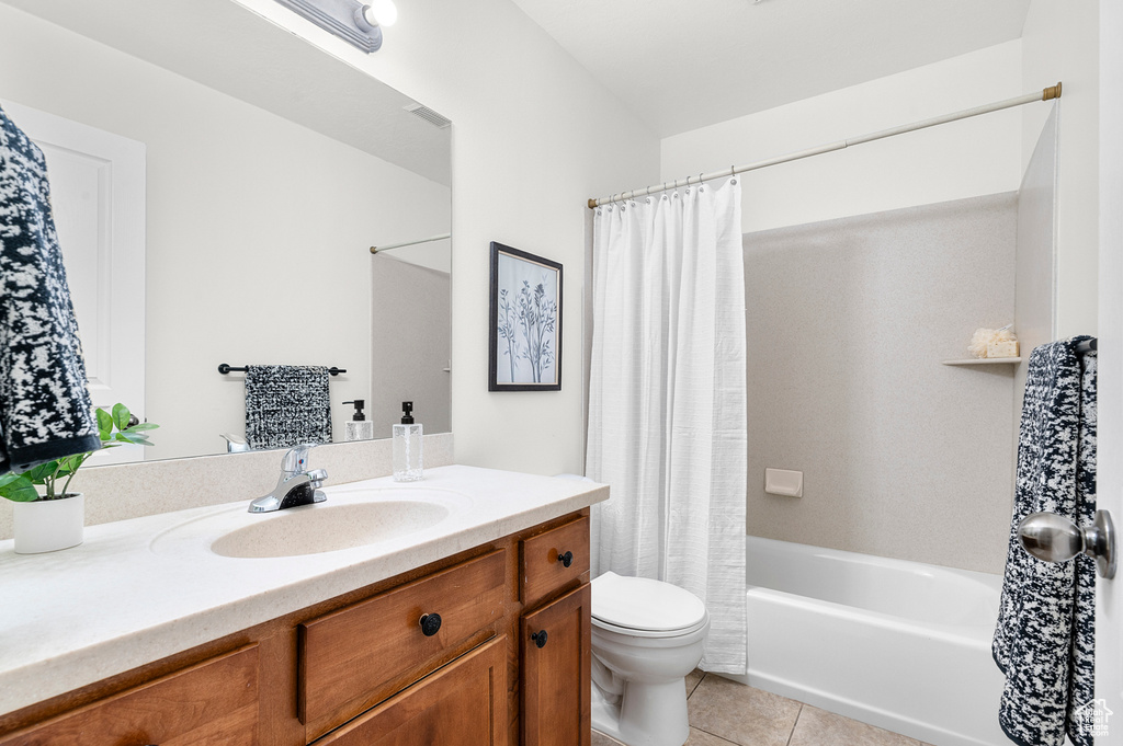 Bathroom featuring vanity, toilet, tile patterned flooring, and shower / bathtub combination with curtain