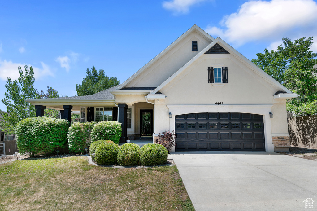 View of front of property featuring stucco siding, driveway, an attached garage, and stone siding