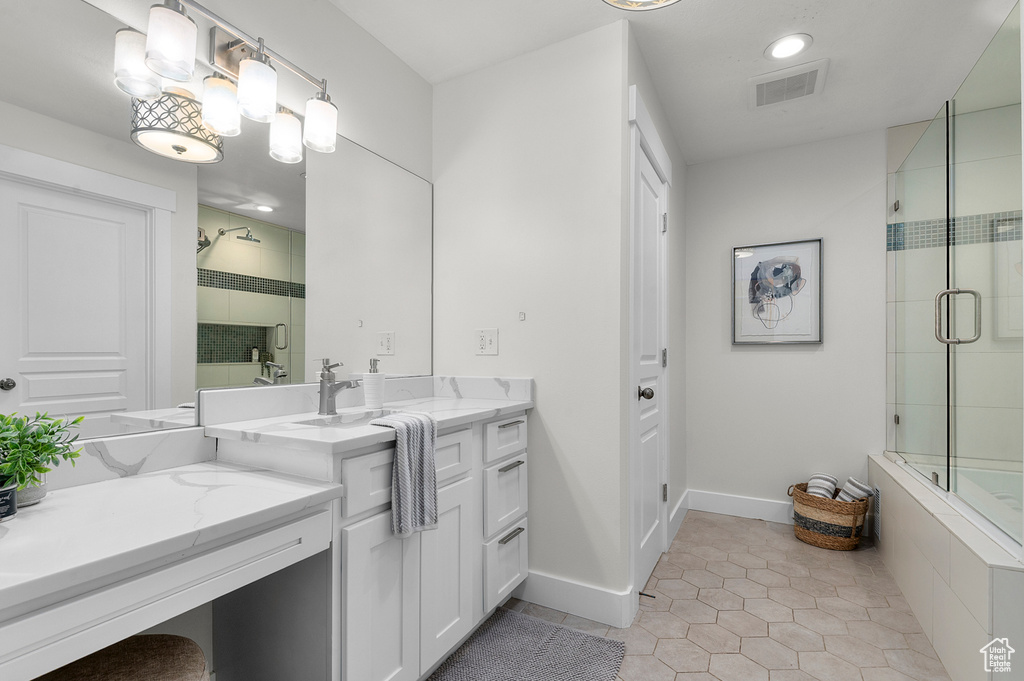 Full bathroom featuring a tile shower, vanity, baseboards, tile patterned flooring, and recessed lighting