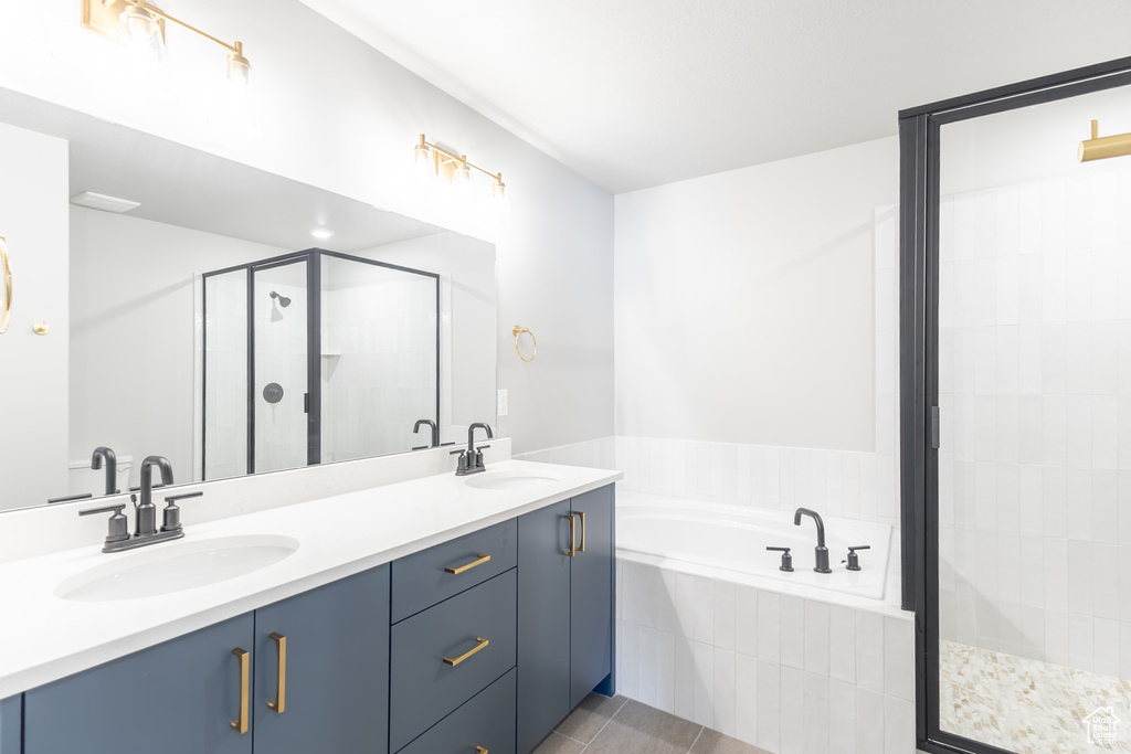 Bathroom featuring a stall shower, a bath, double vanity, and tile patterned flooring