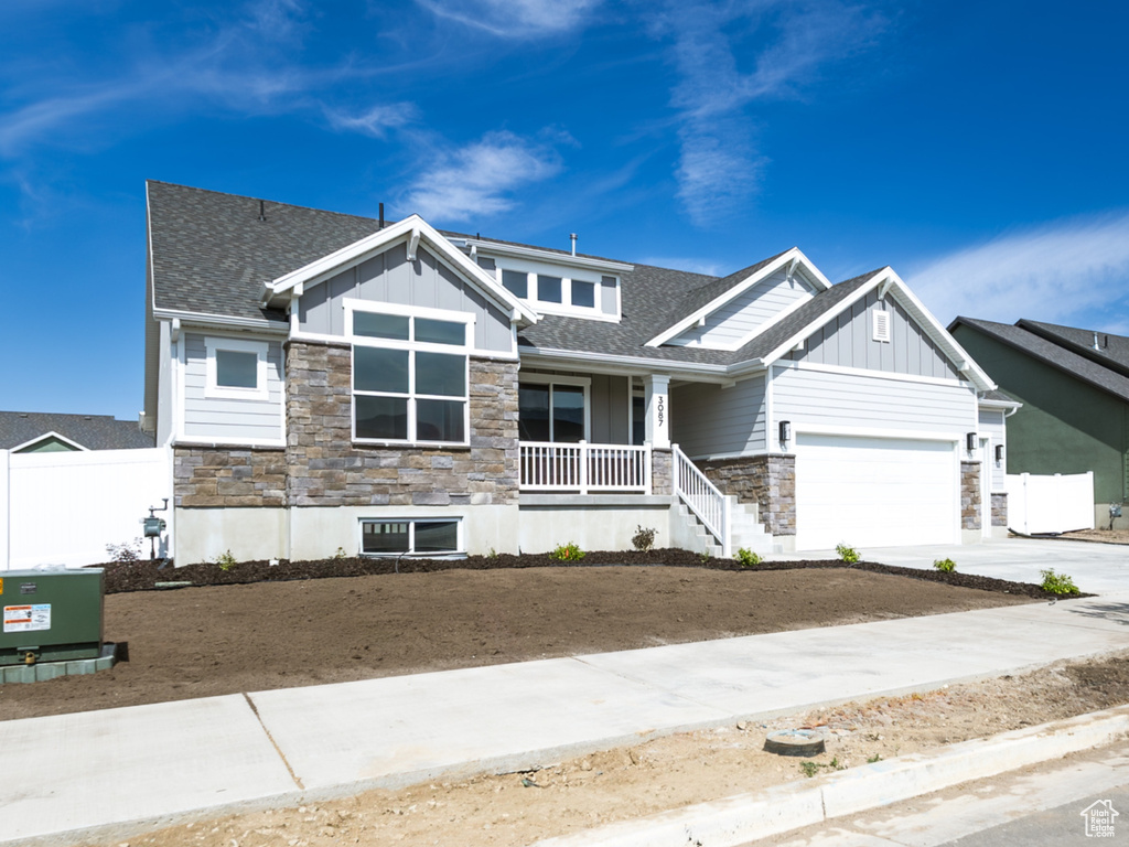 Craftsman house with stone siding, board and batten siding, an attached garage, and driveway