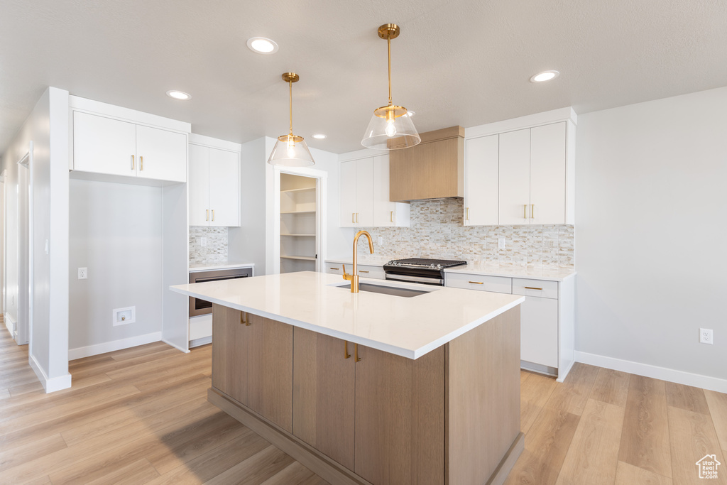 Kitchen featuring a sink, tasteful backsplash, light wood-type flooring, white cabinetry, and recessed lighting