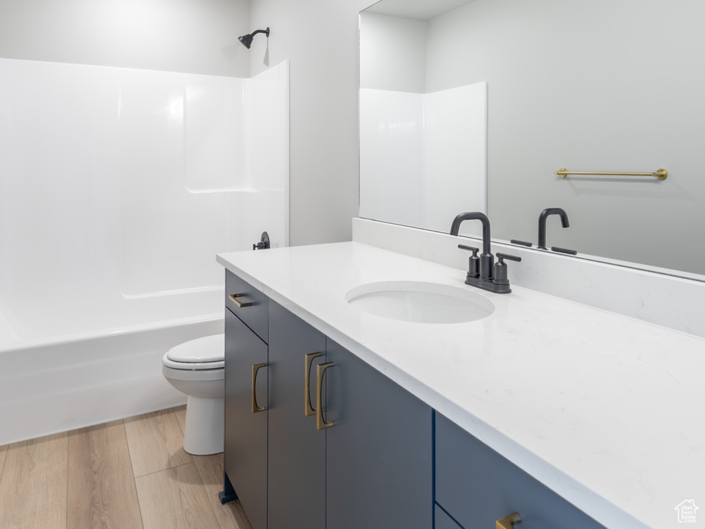 Bathroom featuring vanity, toilet, bathing tub / shower combination, and wood finished floors