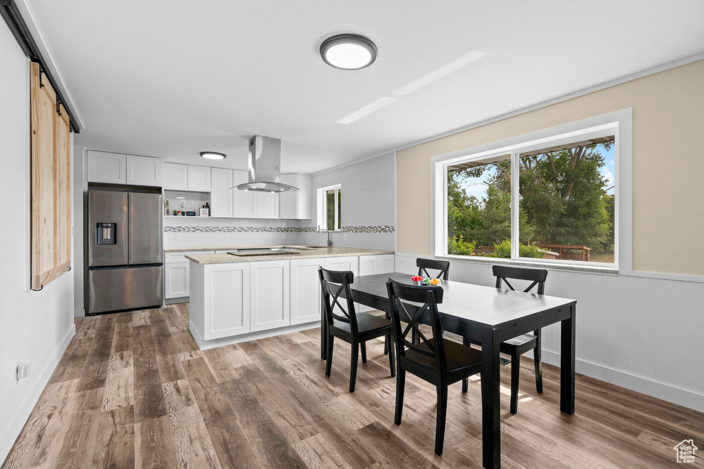 Dining room with wood finished floors, a barn door, and baseboards