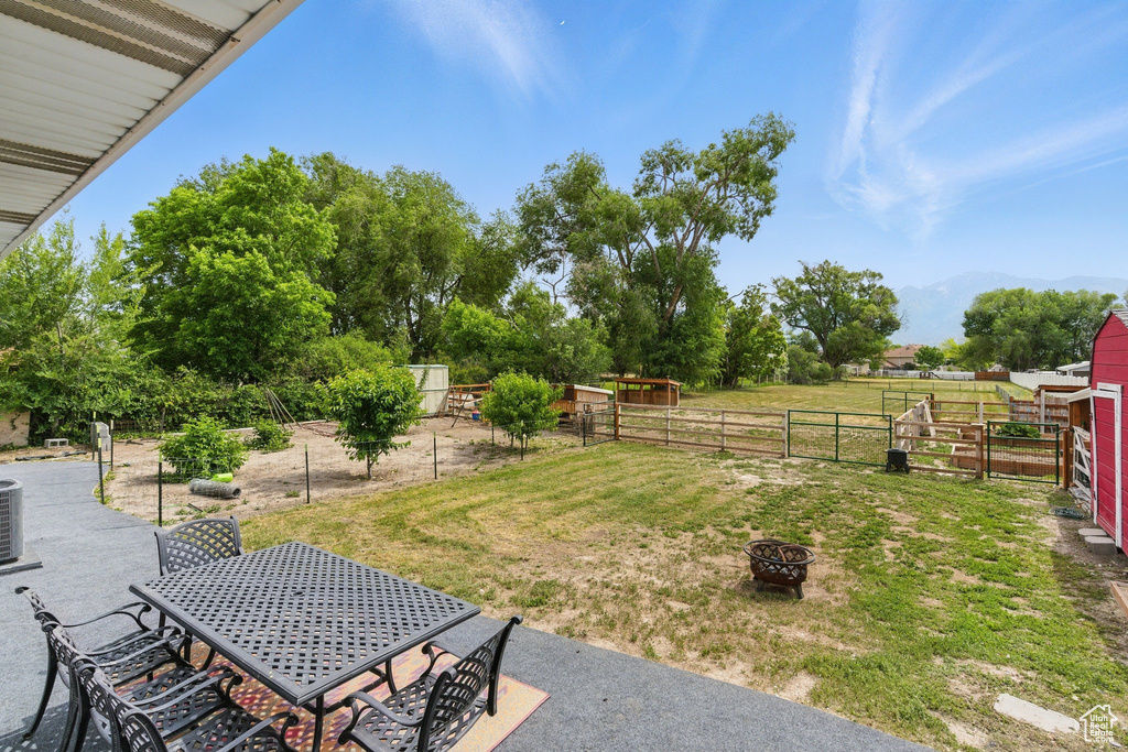 View of yard with a fire pit, outdoor dining area, cooling unit, and a mountain view